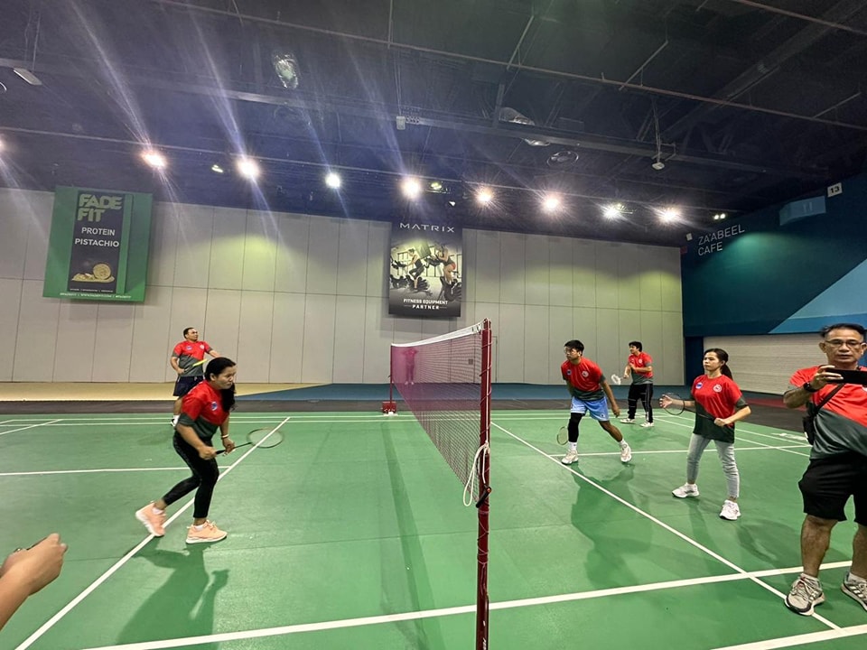 Players in red shirts competing in a badminton doubles match