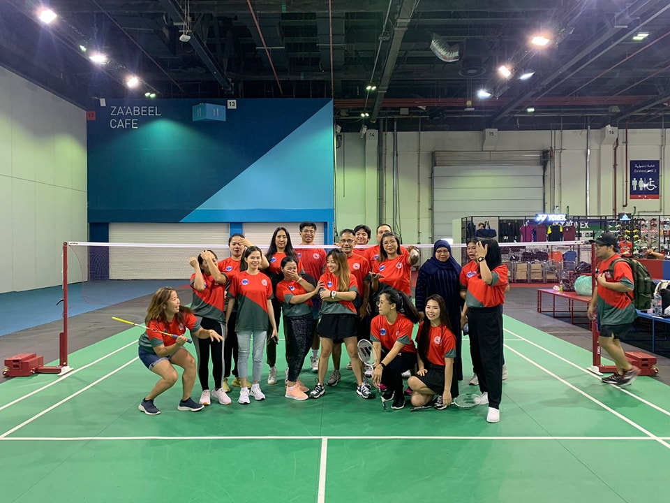 A group posing together on a badminton court after a match